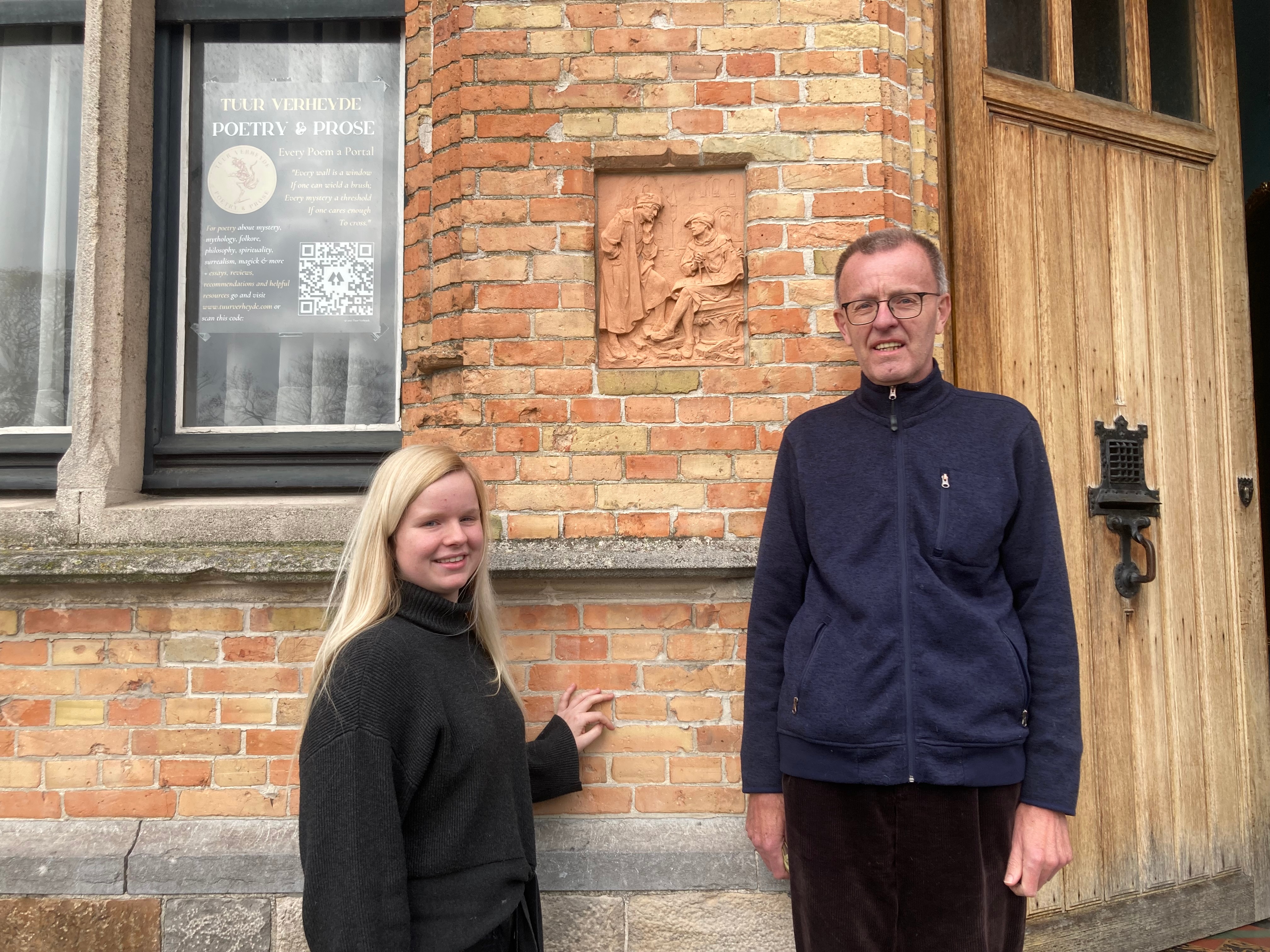 Erwin en Sien Verheyde voor de woning aan het Colaertplein 7 in Ieper. Het terracotta wandpaneel geeft een ‘bouwmeester en leerling-tekenaar’ tafereel weer. 